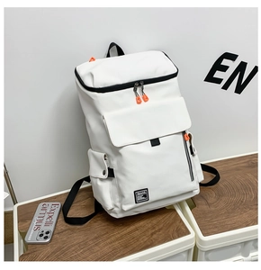 Detail of white nylon backpack with black trim, orange zippers on wooden background