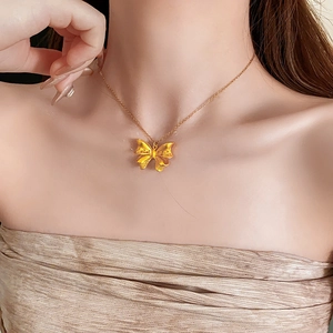 Close-up of elegant gold bow pendant necklace on model showcasing textured metal details