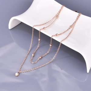 Rose gold double-layer necklace with small beads and round zircon pendant on white ceramic
