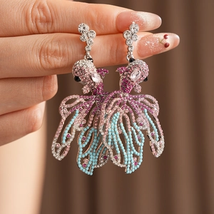 Gros plan de boucles d'oreilles poisson vintage argentées avec strass colorés en main