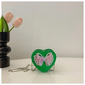 Detail of green heart-shaped crossbody bag with 3D butterfly and silver chain strap