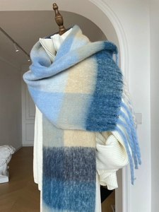 Detail shot of fluffy gradient plaid scarf with long tassels on a white sweater