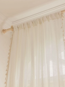 Macro detail of creamy white curtains with woven texture, hollow design, and fringe tassels