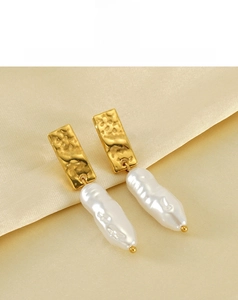 Detail of gold hammer-textured metal earrings with baroque pearls on satin fabric
