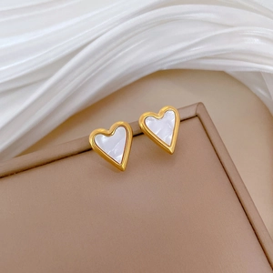 Detailed macro view of heart-shaped white mother of pearl earrings with gold steel trim