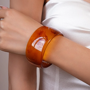 Close-up of wide amber resin bangle with tortoiseshell pattern on a model's wrist