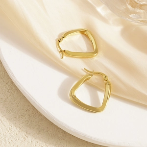 Polished gold U-shaped geometric earrings on elegant silk background with soft lighting