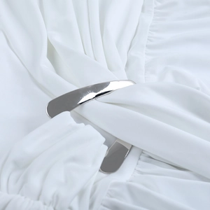 Close-up of white ruched fabric with a silver metallic curved buckle on a summer dress