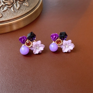 Nahaufnahme von Vintage-Blumenohrringen mit lila Harzrosen und bernsteinfarbenen Kristallen