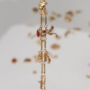 Close-up of golden bow earrings with red gemstone and cross pendant detail