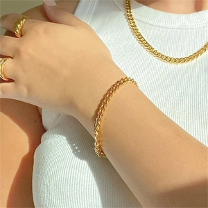 Close-up of gold Cuban link jewelry set including necklace, bracelet and rings on model