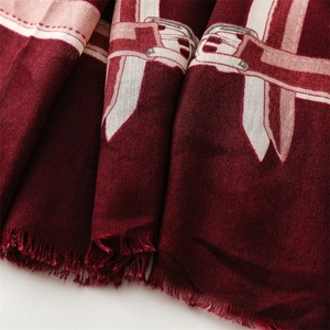 Close-up of deep red scarf with belt buckle patterns and fringe detail on white background