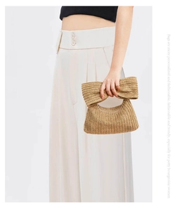 Detail of handwoven straw handbag with bow knot design for elegant summer style