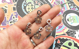 Macro shot of 4 hollow heart cherry blossom charms in gold and silver plating