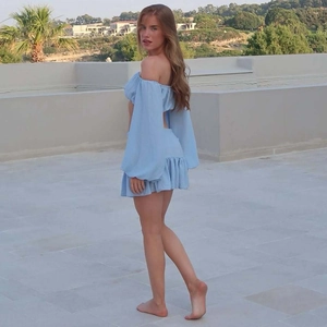 Dettaglio del set blu top corto a maniche lunghe scollato e minigonna su una terrazza soleggiata