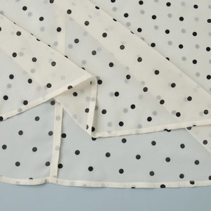 Detailed close-up of polka dot fabric showing hem stitching and lightweight texture