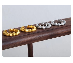 Detail of gold and silver gear-patterned titanium rings on a dark wood display stand