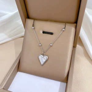 Detail of silver heart necklace with white pearl inlay inside an elegant jewelry box