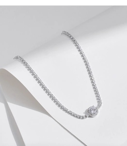 Détail macro du collier tennis en argent avec pendentif halo sur fond minimaliste