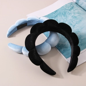 Close-up of velvet padded wave headbands in black and blue with handmade labels