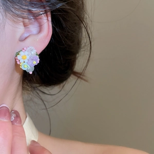 Primer plano de pendientes de flores de cristal de colores puestos en la oreja