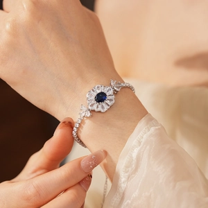 Nahaufnahme eines silbernen Blumenarmbands mit blauen Steinen und Zirkonia am Handgelenk