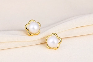Macro shot of S925 silver flower pearl stud earrings with gold five-petal design