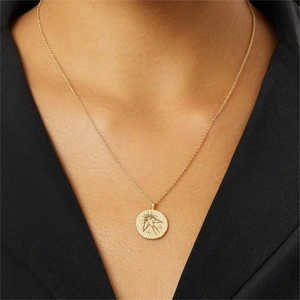 Golden stainless steel coin necklace with bird and star elements on model