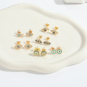 Evil Eye and small fish stud earrings set with blue cubic zirconia on ceramic tray