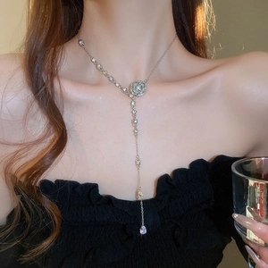 Close-up of silver Y-shaped necklace with diamond flower and water drop tassel pendant