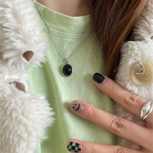 Detailed view of an oval black gemstone necklace paired with a wide silver ring