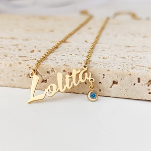 Macro shot of custom Lolita name necklace in gold with a small blue birthstone pendant