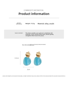 Détail de boucles d'oreilles pendantes ovales en acrylique bleu et métal doré