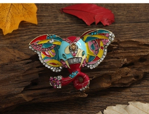 Artistic elephant brooch with colorful enamel and rhinestones on rustic dark wood background