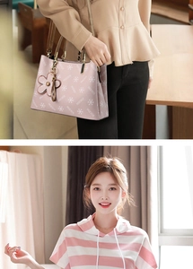 Pink printed crossbody bag with floral pendant shown by model in lifestyle setting