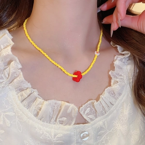 Close-up of handmade yellow and red beaded necklace with flower pendant on neck
