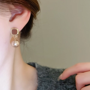 Close-up of vintage square oil-drop earrings with champagne faux pearls on a model