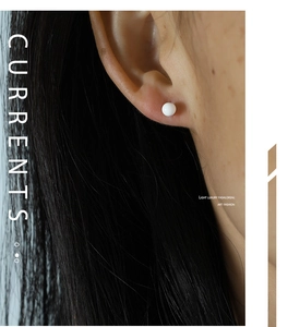 Detailed view of a white round pearl stud earring worn on the earlobe for a minimalist look