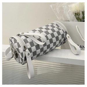 Detailed view of checkered cylinder bag with wide shoulder strap and textured surface