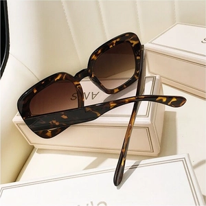 Detail view of retro tortoiseshell square sunglasses on white premium gift packaging