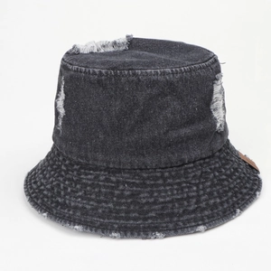 Détail du chapeau bob en jean délavé avec trous effilochés et écusson en cuir