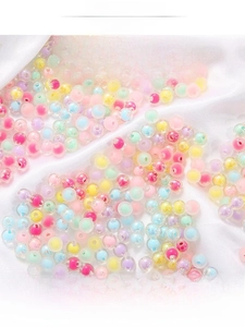 Detailed view of colorful layered acrylic beads for DIY jewelry on white silk fabric