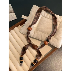 Detailed macro view of ethnic style necklace featuring brown floral fabric and wooden beads