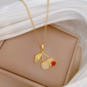 Detailed shot of golden cherry necklace with red and clear crystals on silk fabric