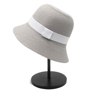 Detail of gray straw bucket hat with a white ribbon bow on a display stand