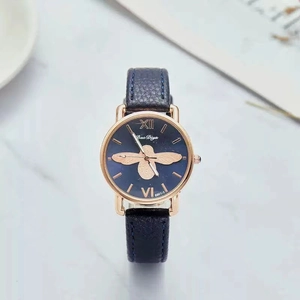 Detail of luxury bee motif watch on marble surface with dark blue leather strap