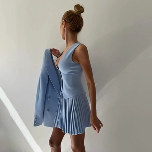 Détail de la robe gilet sans manches bleu clair et de la jupe plissée avec un blazer assorti