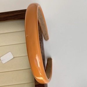 Detailed close-up of glossy bright orange headband with brown non-slip velvet inner lining