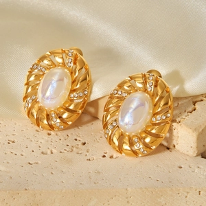 Dettaglio macro di orecchini di perle in oro 18k con zirconi su superficie di roccia