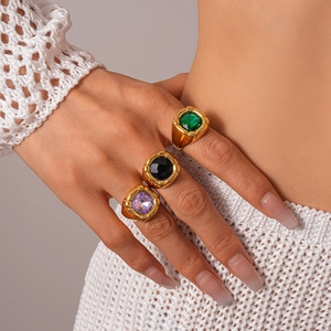 Close-up of three vintage gold rings with emerald, black, and purple square gemstones